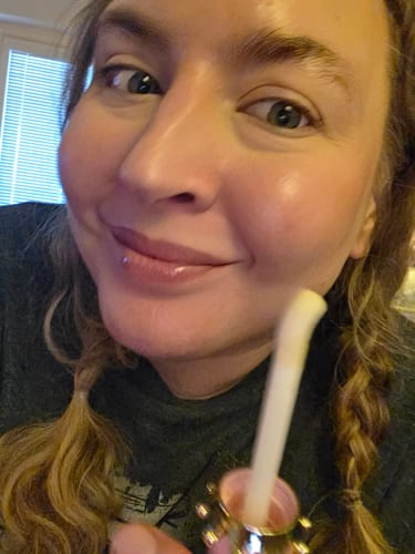 Close-up of a reviewer smiling with glossy lips, holding the P.Louise Bad Bitch Energy Lip Duo.