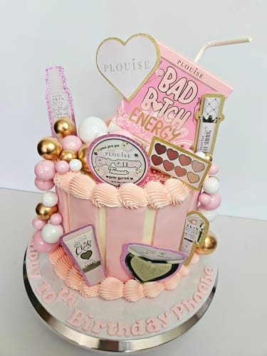 A customer's pink birthday cake decorated with cutouts of the Bad Bitch Energy Lip Duo packaging.