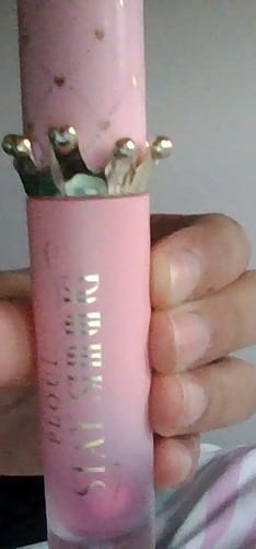 Close-up: Reviewer holding the pink Bad Bitch Energy lip oil with a decorative gold crown cap.