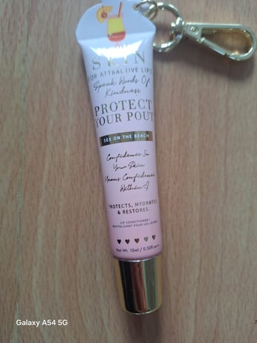 Reviewer's 'Protect Your Pout' lip conditioner from the Bad Bitch Energy Lip Duo, shown with its keychain attachment.