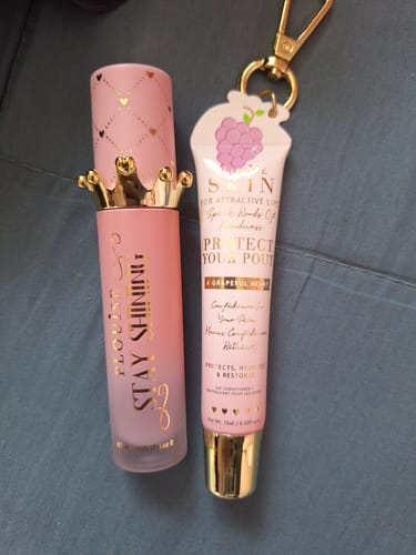 Customer's Bad Bitch Energy Lip Conditioner & Lip Oil Duo, featuring pink and gold packaging, on a grey surface.