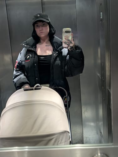 Customer taking a mirror selfie in an elevator while pushing a stroller.