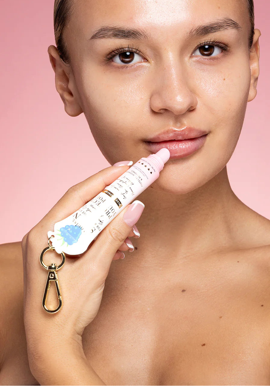 Woman applying a skincare product to her face against a pink background